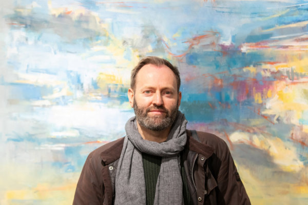 Alex Duncan standing in front of one of his paintings